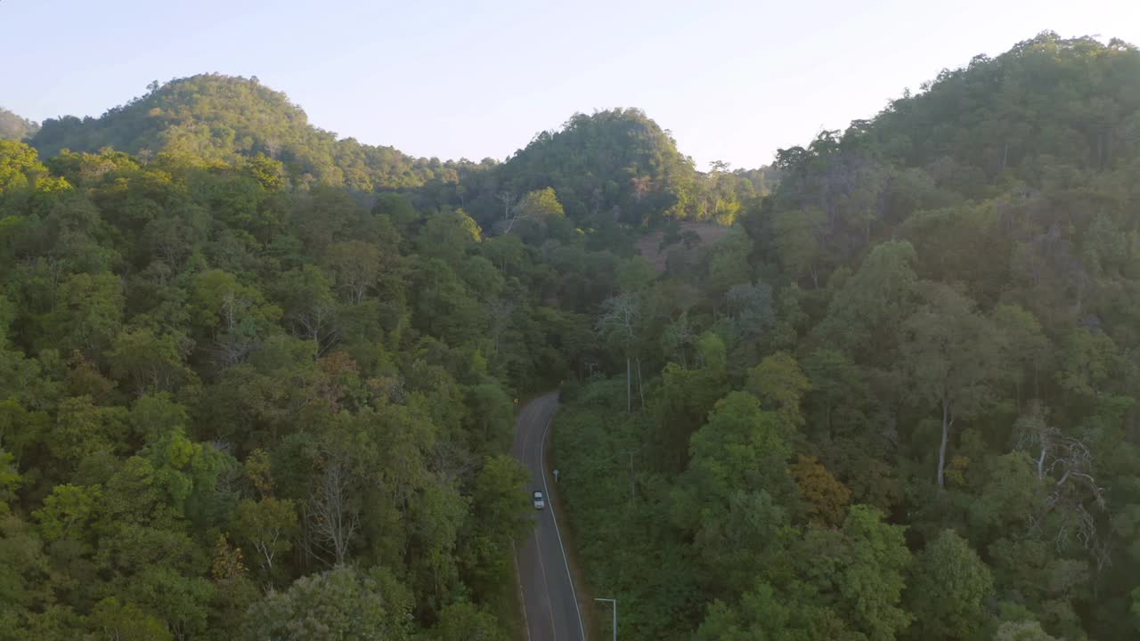 鸟瞰图上的汽车行驶在弯曲，曲折曲线的道路或街道上的山与绿色的天然森林树木在农村地区的南，泰国。交通工具。视频素材