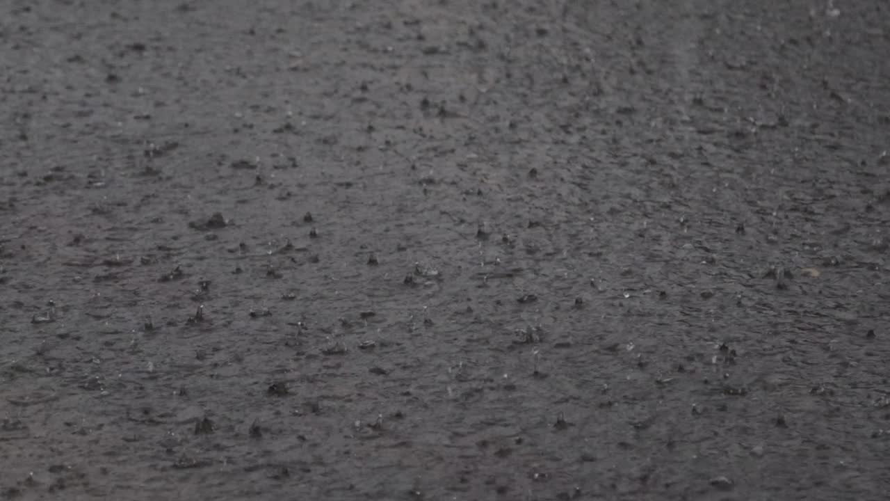 大雨滂沱，雨点在河面上形成不规则的图案视频素材