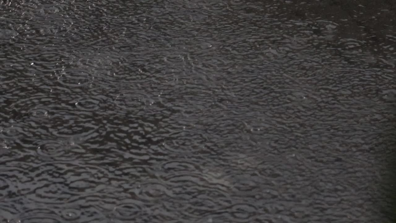 大雨滂沱，雨点在河面上形成不规则的图案视频素材