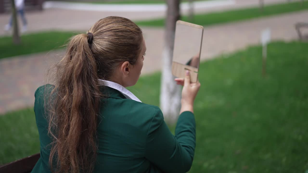 深色皮肤的白种人超重的女人欣赏的反映在手镜坐在城市街道户外。背部角度看自信的成年女性与马尾辫调整化妆在慢动作。视频素材