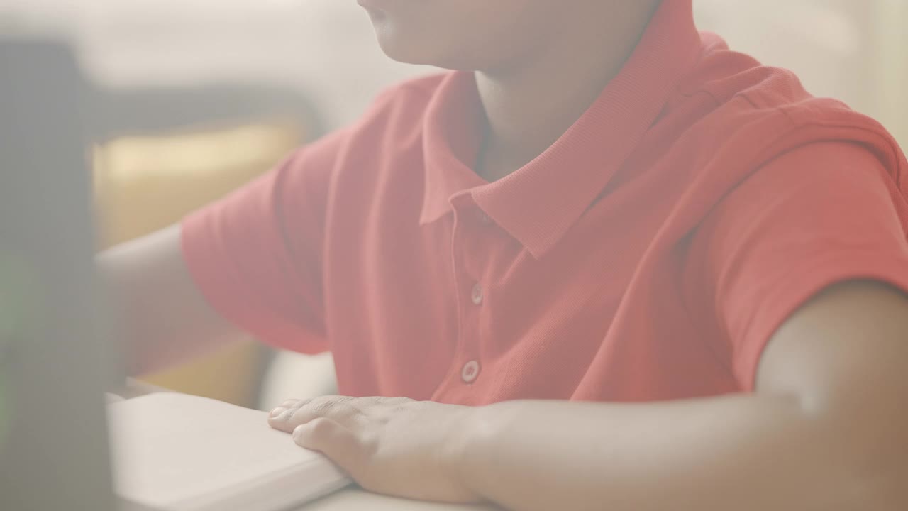 戴着耳机的聪明小学生用笔记本电脑在线学习，远程学习视频素材