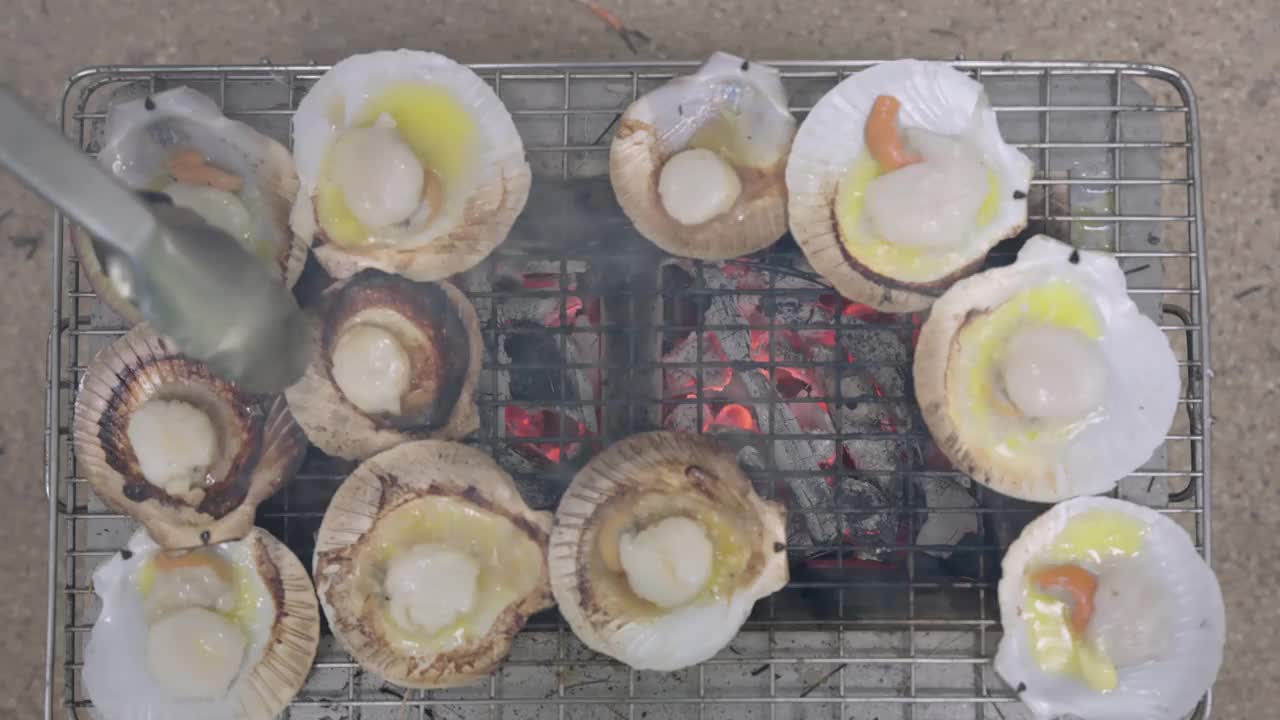 4K，涂了黄油的扇贝在高温木炭烤架上烘烤，等待烹饪后再食用。视频素材