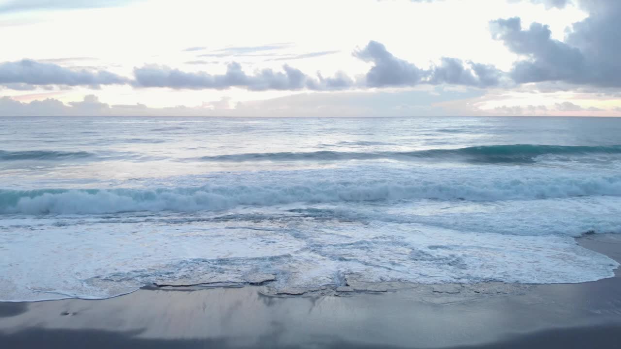 在暴风雨多风的日子里，有岩石和卵石的海岸。巨大的白色泡沫浪冲击着海滩。海上落日，天空多云。在自然的力量。美丽的自然景观视频素材