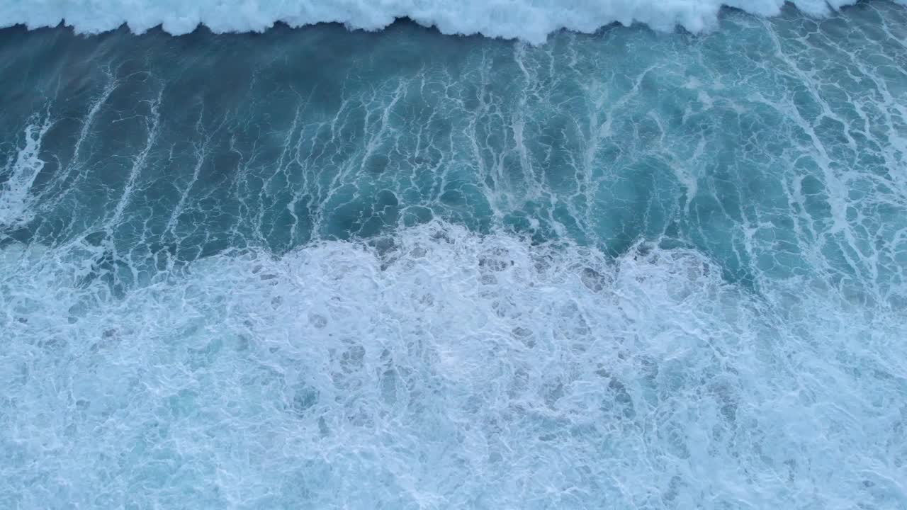 巨大的白色泡沫海浪，俯视图。海浪拍打着岩石。巨浪冲击海岸。蓝绿色的海浪飞溅着泡沫和浪花。美丽的海景视频素材