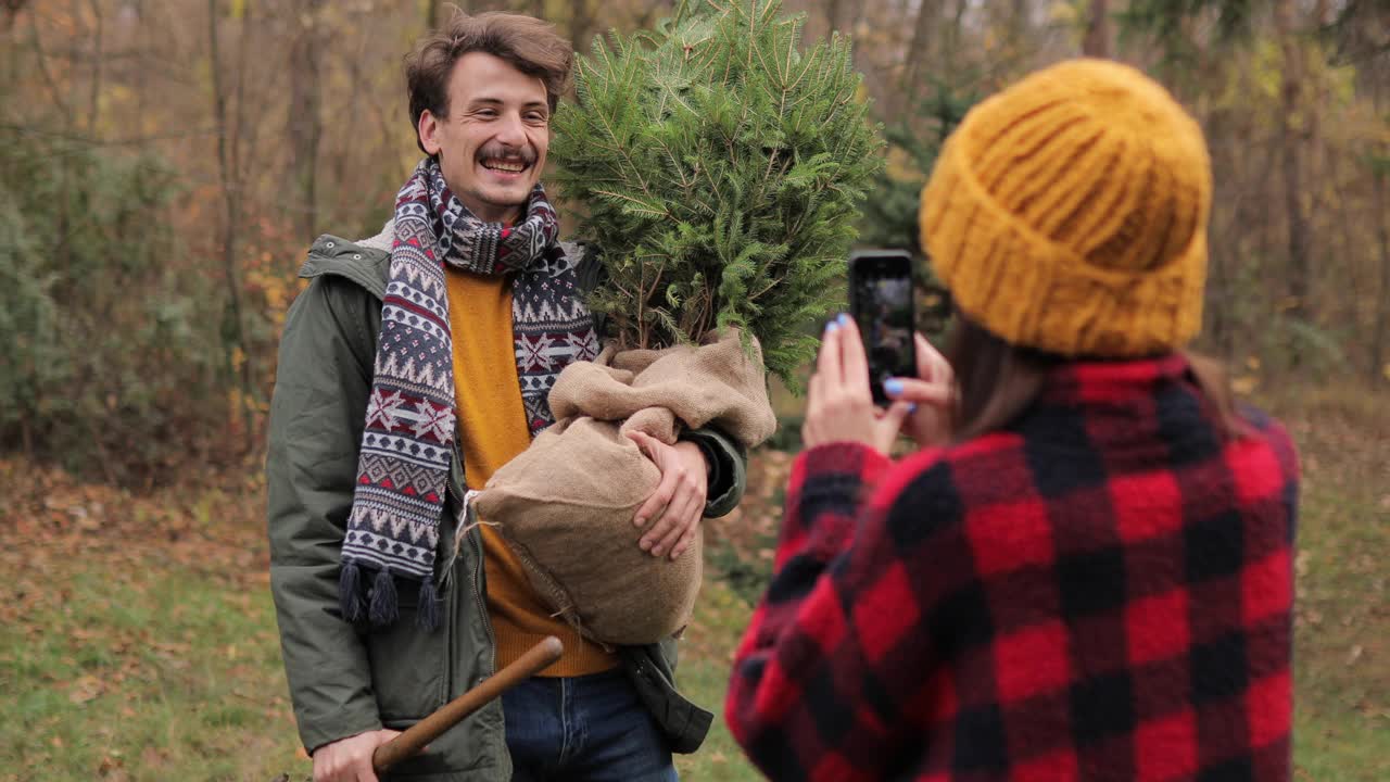 小女孩正在给她的男朋友和新的圣诞树拍照视频素材