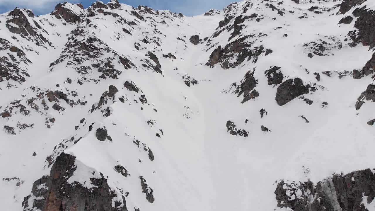 高山中冰雪覆盖的岩石斜坡。陡峭的颜色适合极限滑雪。高级骑手的免费乘车点。鸟瞰图视频素材