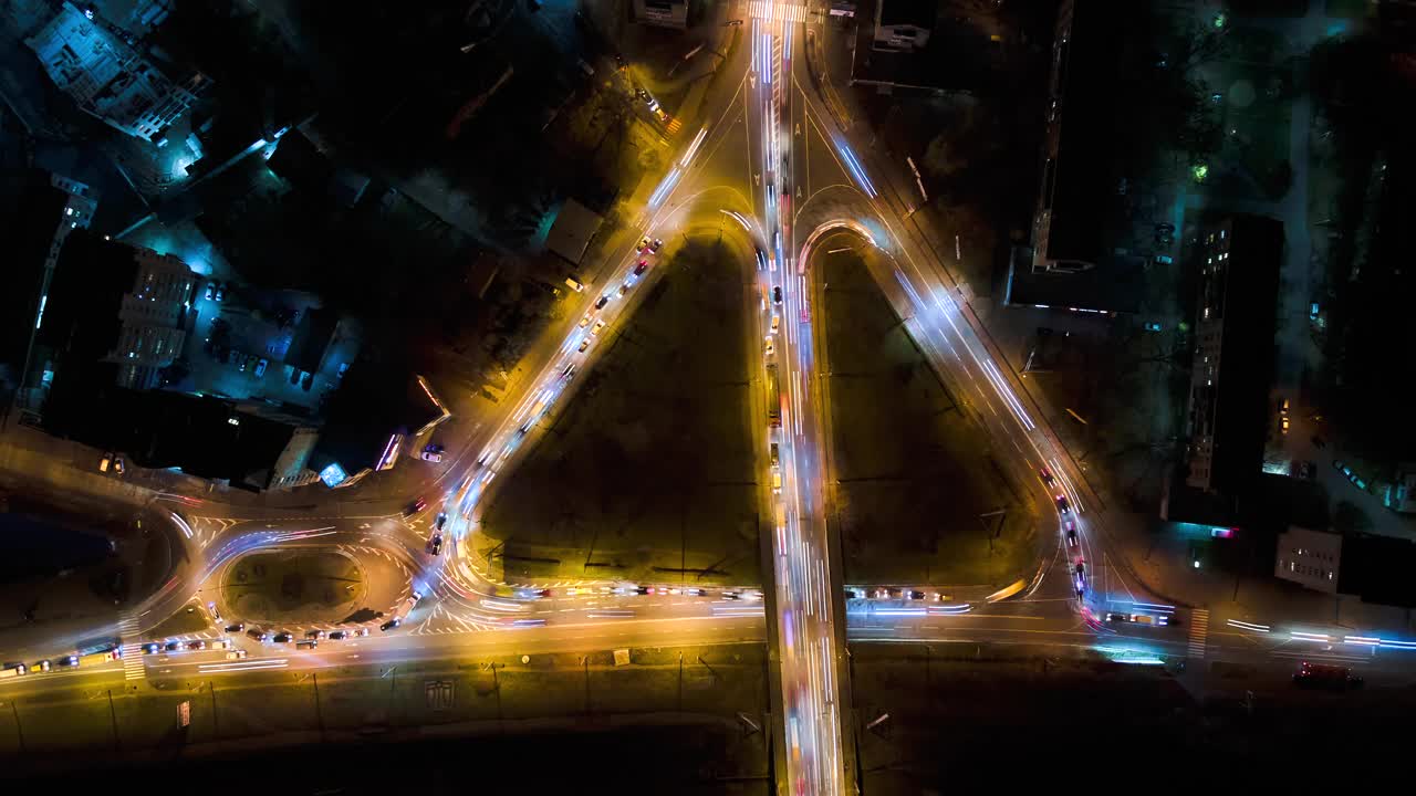 鸟瞰图的道路交叉口快速移动的繁忙的交通在夜间。城市交通的时间间隔。交通高峰期，汽车尾灯模糊不清视频素材