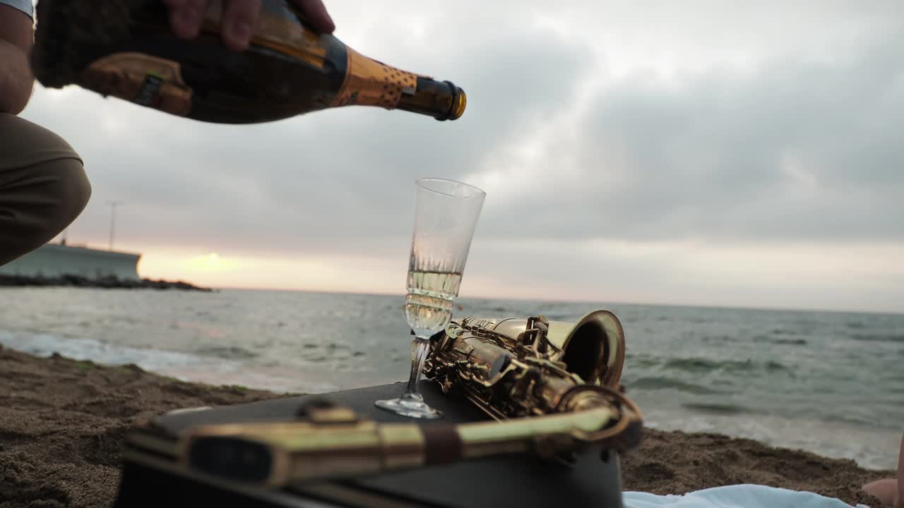 一个男人在太阳的背景下开香槟，黎明在床上。野餐的日期。视频素材