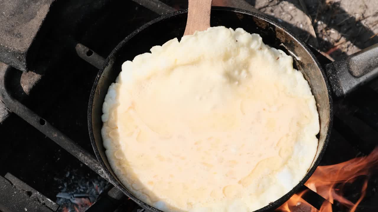 在野外用旅游煎锅在篝火上烹饪煎蛋卷视频素材