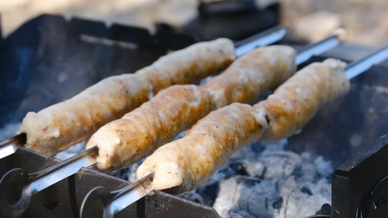 烤串香肠在户外便携式烧烤机上烹饪，特写，烧烤视频素材