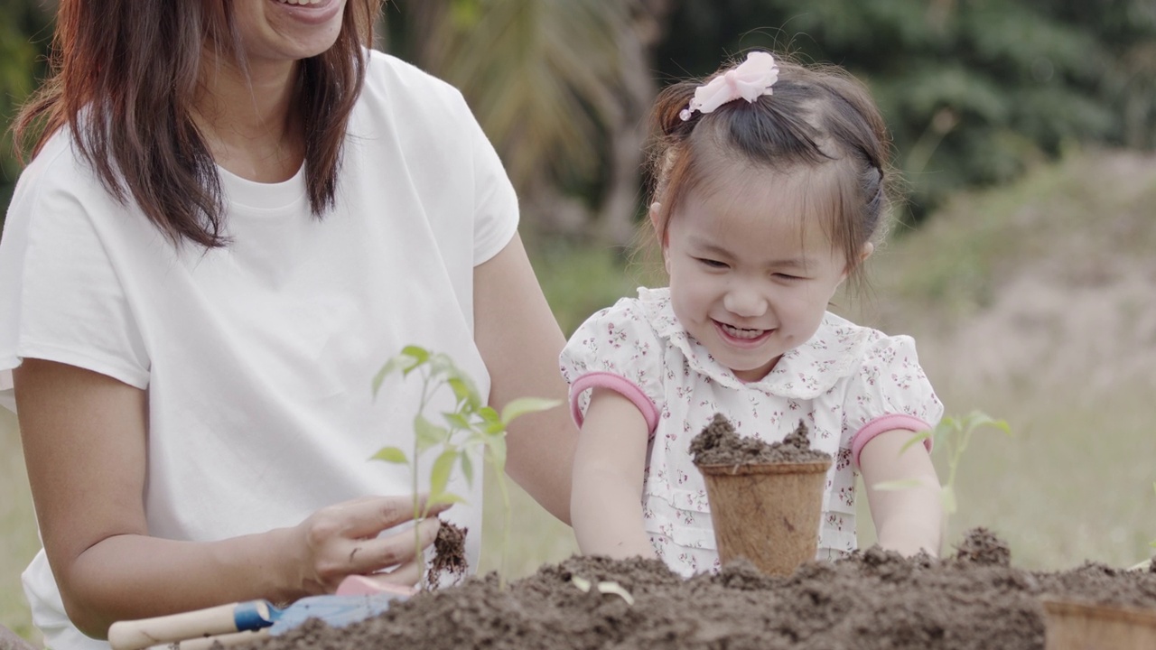 亚洲小女孩和父母种植幼苗到土壤视频素材