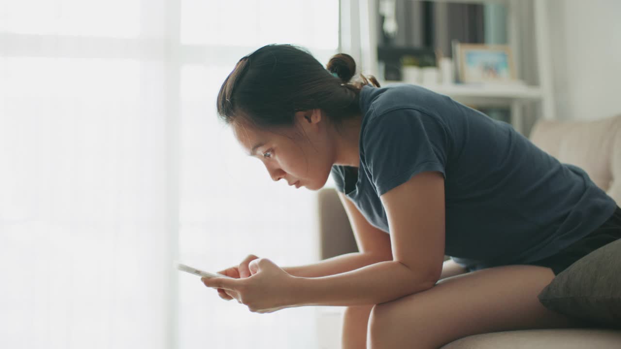 一个女人在沙发上使用智能手机视频素材