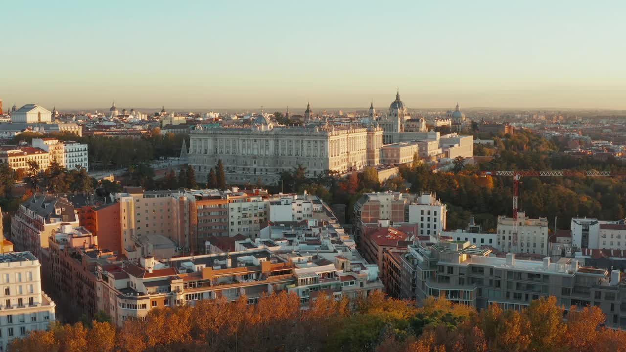 低空飞行于市区公园和建筑物的树木上方。夕阳映照下雄伟的皇家宫殿视频素材