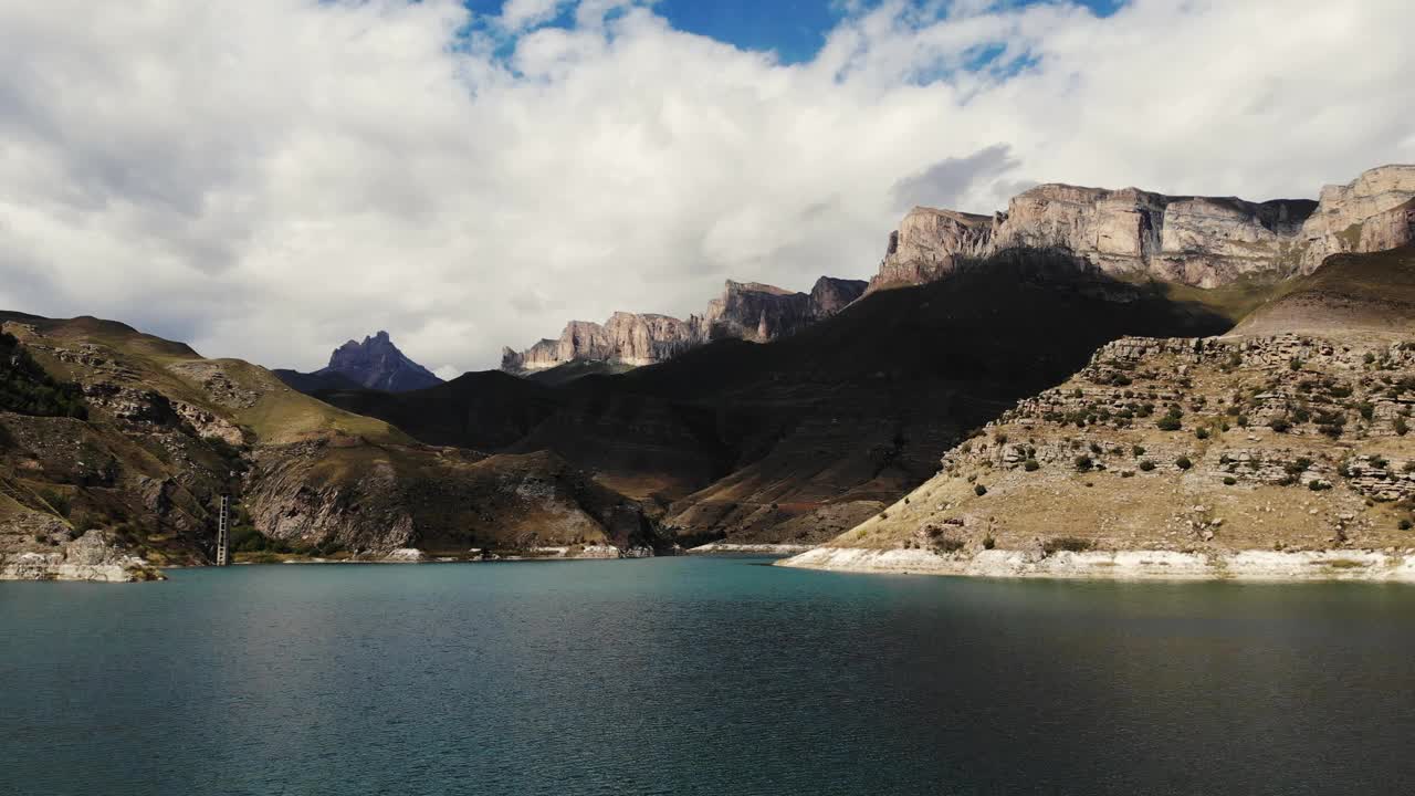 俯瞰高加索地区吉日吉特蓝色山湖。蓝色的海水在阳光下闪烁。巍峨的山脉依稀可见。尖尖的山峰在多云的天空映衬下闪闪发光。无人机videoshooting视频素材