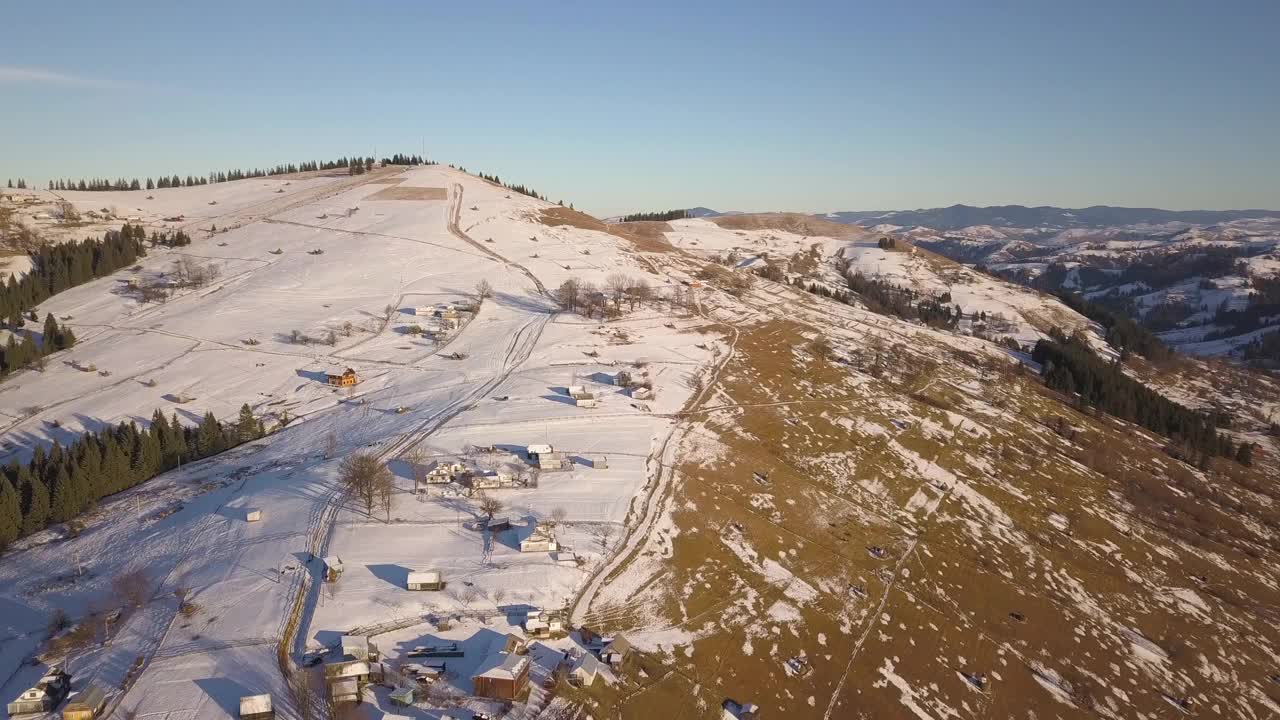 鸟瞰图，在乌克兰的喀尔巴阡山脉，冬天白雪覆盖的山丘上散落着房屋视频素材