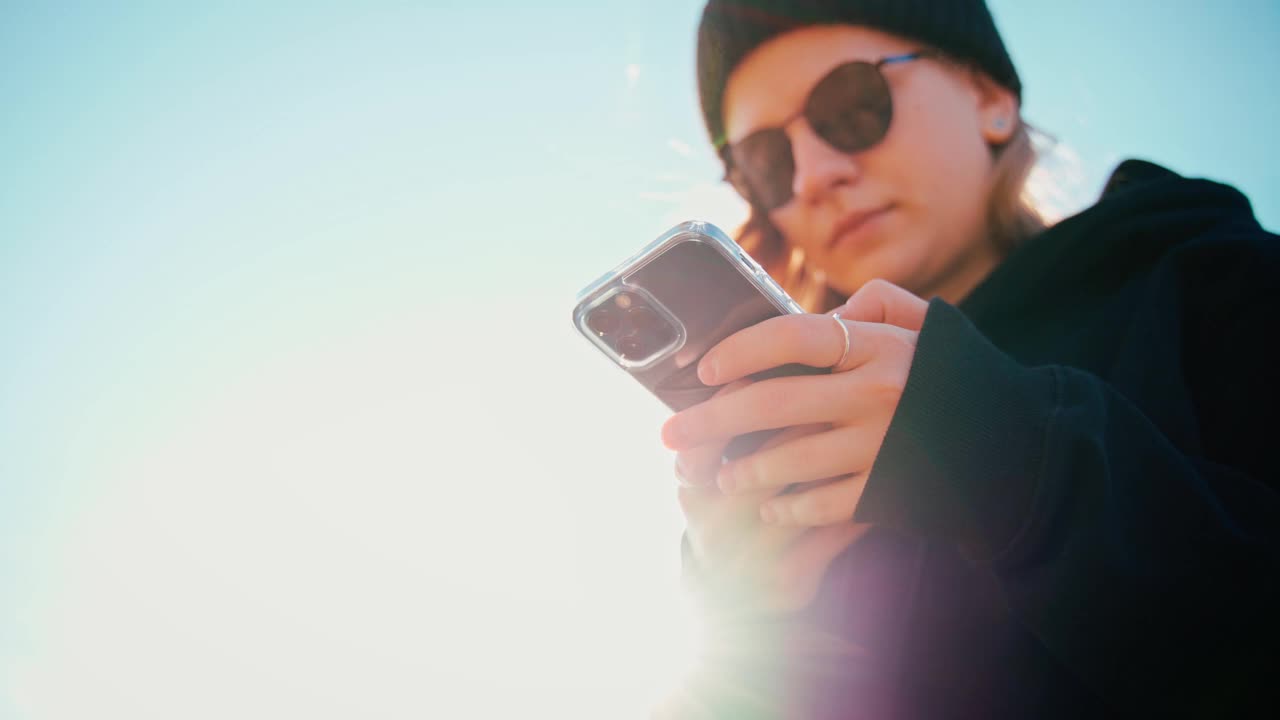 一位戴着太阳镜的迷人年轻女子正在用手机发短信视频素材