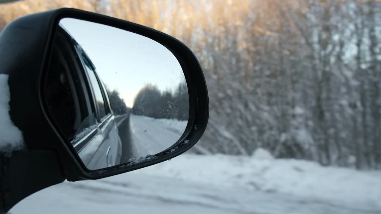 冬季森林道路的侧视镜反射。风景与空旷的高速公路穿过雪原森林。汽车在路上超速行驶。汽车在运动。旅游，旅行，旅行概念。冰雪覆盖的树木。视频素材