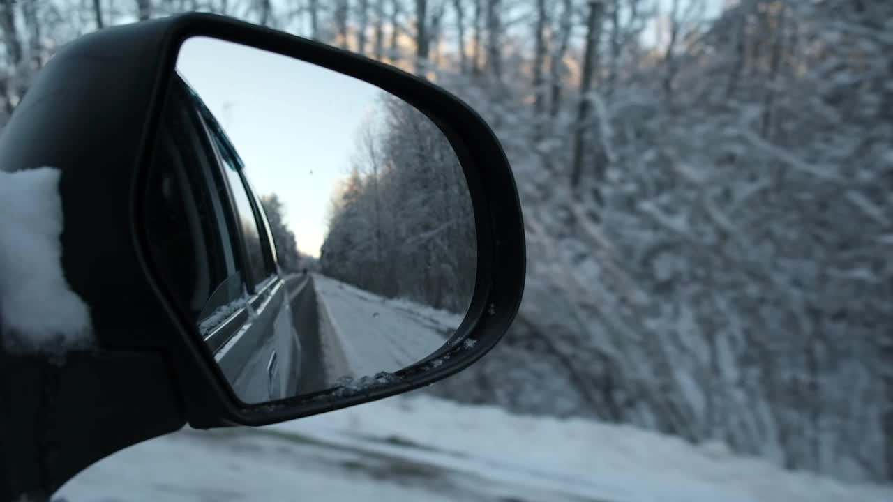 侧视镜反射冬季森林道路。风景与空荡的公路穿过白雪森林。汽车在道路上超速行驶。汽车在运动。旅游、旅游、旅行的概念。冰雪覆盖的树木。视频素材