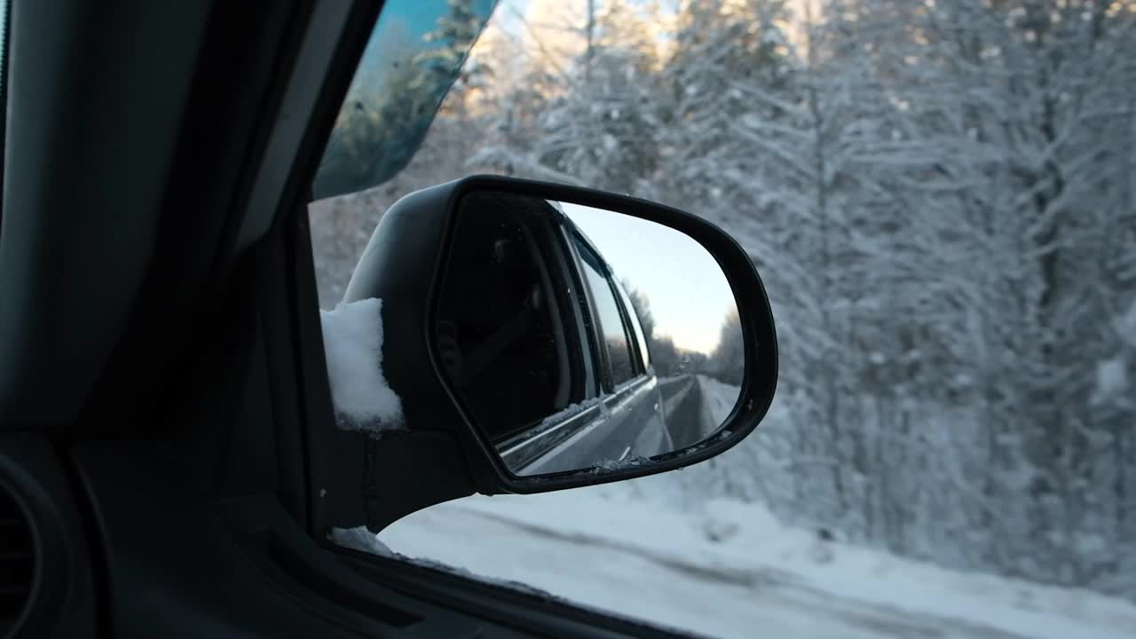 冬季森林道路的侧视镜反射。风景与空旷的高速公路穿过雪原森林。汽车在路上超速行驶。汽车在运动。旅游，旅行，旅行概念。冰雪覆盖的树木。视频素材