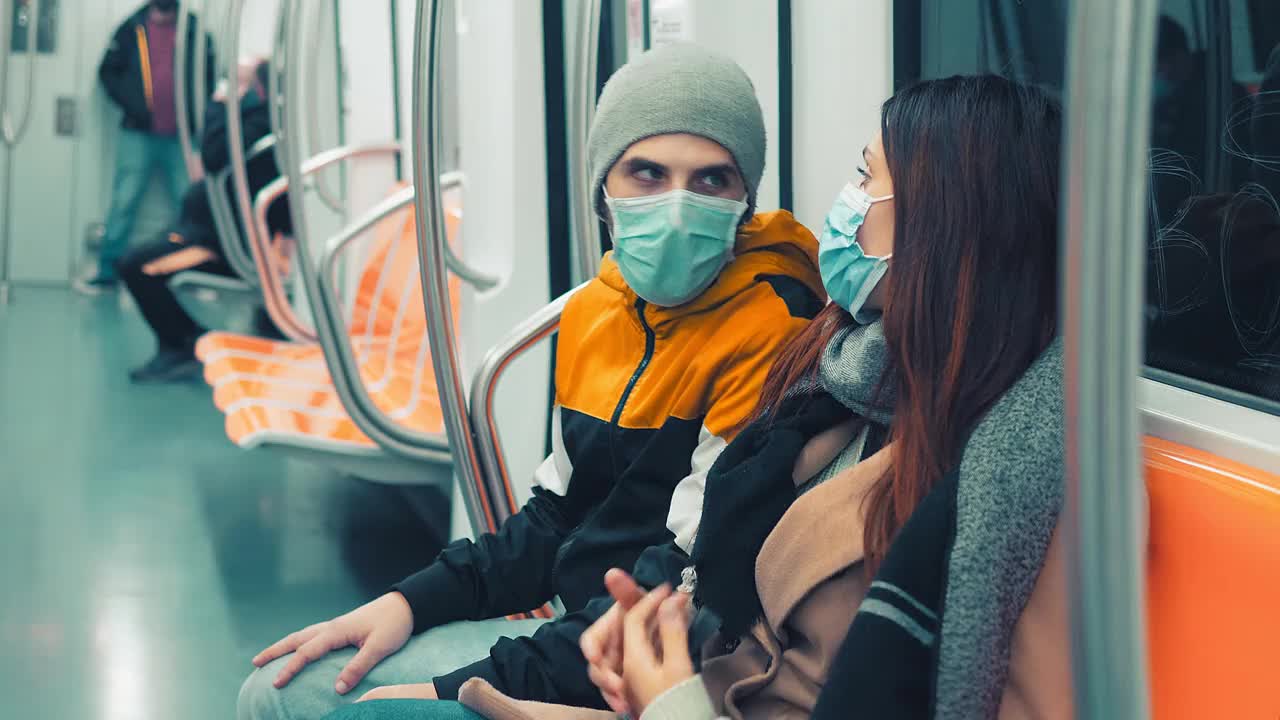 疫情期间的公共交通——年轻夫妇戴着口罩乘坐地铁视频购买
