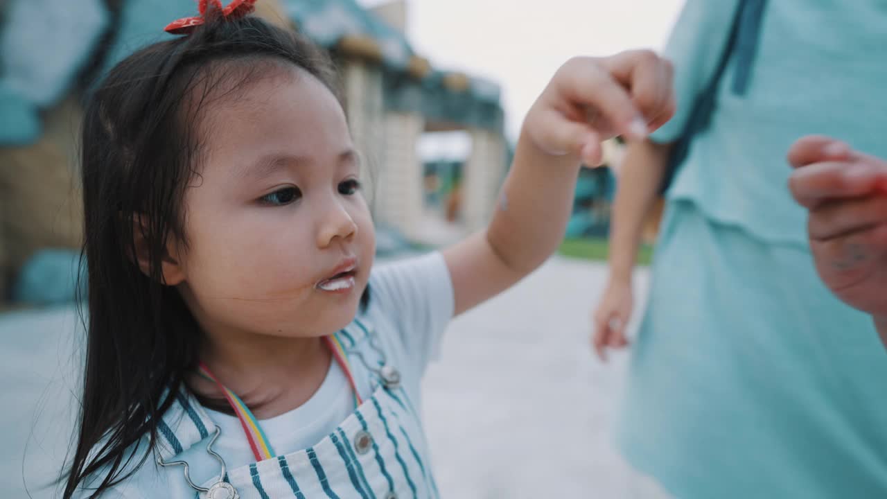 可爱的孩子在户外公园里分享冰淇淋视频素材