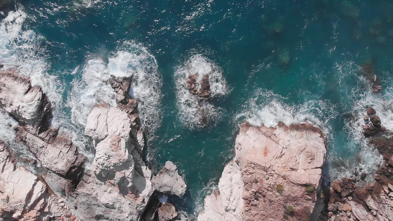 多岩石的海岸景观。白色泡沫的波浪拍打着岩石海岸。碧蓝清澈的海浪拍打着岩石海岸的美丽景色。神奇的海景视频素材