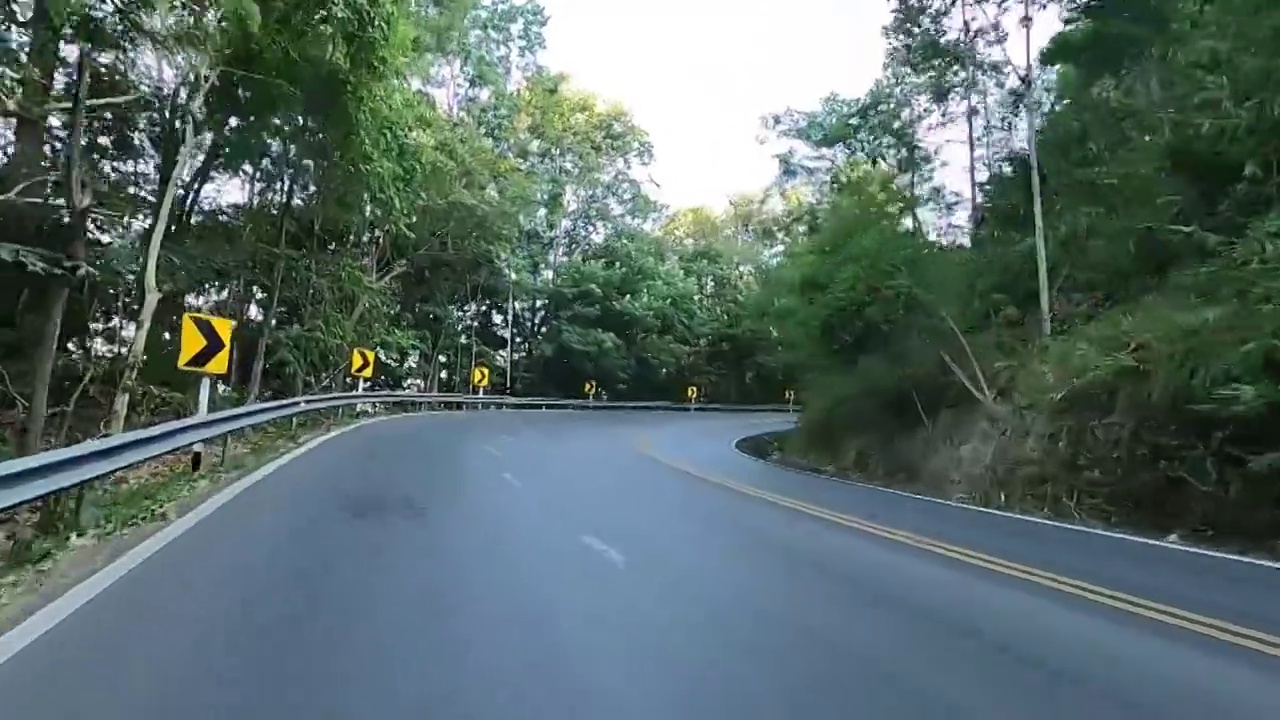 骑摩托车在自然阳光山景与弯曲的道路。视频素材