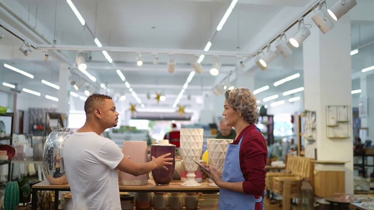 一名男子在家具店接受女售货员的帮助视频素材