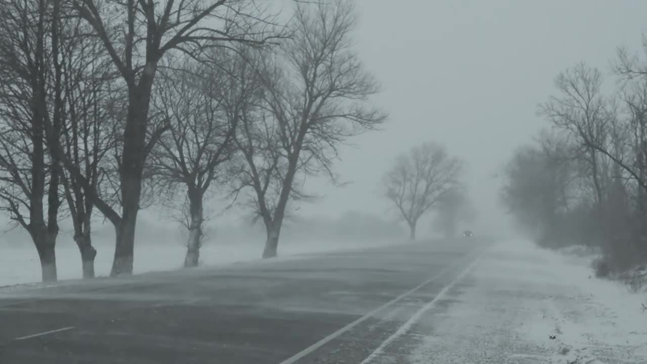 暴风雪中行驶在冬季道路上的汽车视频素材