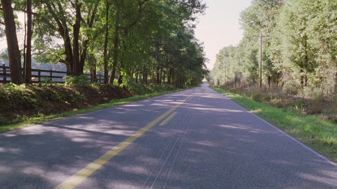 双车道公路广角。林区树木和围栏从农场侧翼乡村道路。视频素材