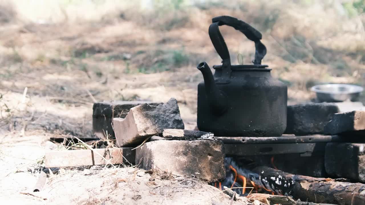 旅游水壶站在一个自制的篝火炉在旅游营地的自然视频素材