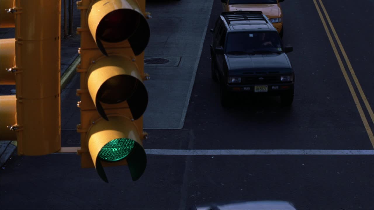 高角度下的汽车通过一个十字路口的两车道的道路。绿灯信号灯在fg中可见的信号灯或交通信号视频素材