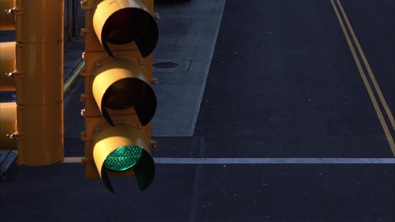 两车道道路上方的红绿灯或交通信号灯的高角度向下。灯光从绿色变成黄色。视频素材