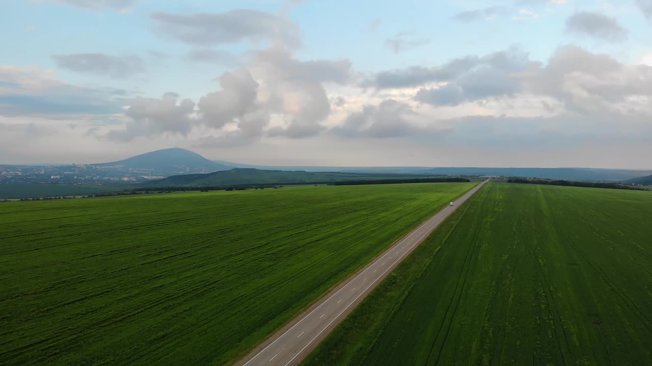 在公路上有汽车驾驶的空中飞行。美丽的风景公路之间的绿地。通往远方的路视频素材