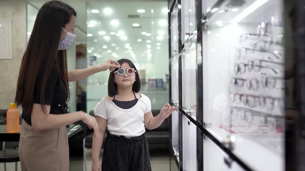 亚洲华裔女性眼科医生在检查光学实验室使用试验框架与儿童患者。视频素材