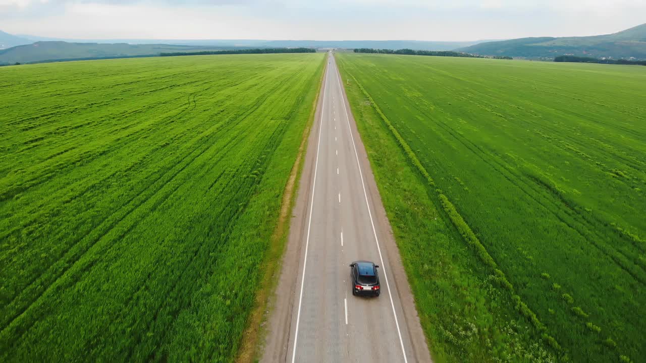 4 k鸟瞰图。无人机正在跟踪一辆在农田间行驶的汽车。在车上冒险。俯视图到移动的汽车。旅行的概念。视频素材