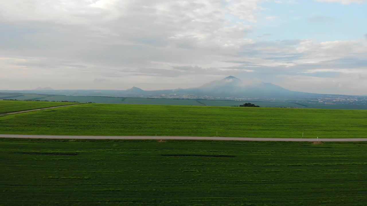 无人机视角:夏日阳光明媚，白色卡车行驶在城际高速公路上，穿过风景如画的农田驶向客户。配送物流货物，鸟瞰运动视频素材