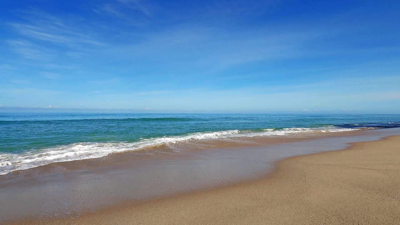 海军蓝的海水和海浪冲击着深棕色的沙滩视频素材