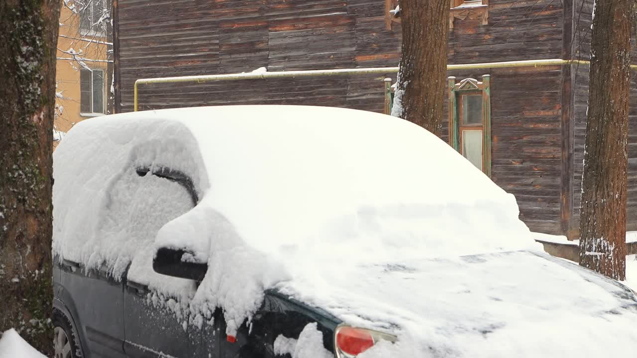 一个男人用刷子清理汽车挡风玻璃上的雪。视频素材