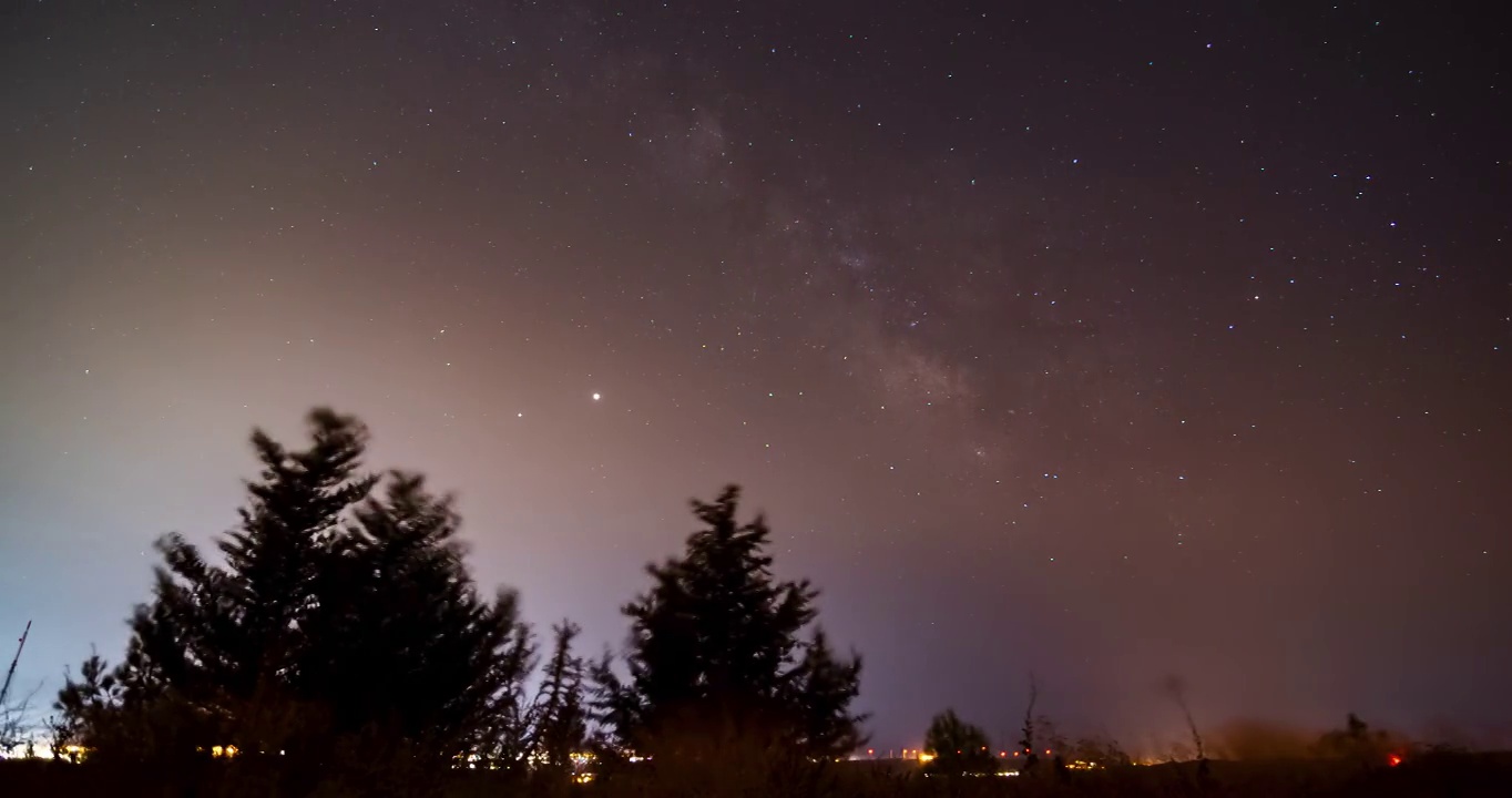 塞浦路斯一个明亮的城市上空的星星和银河的延时视频视频素材