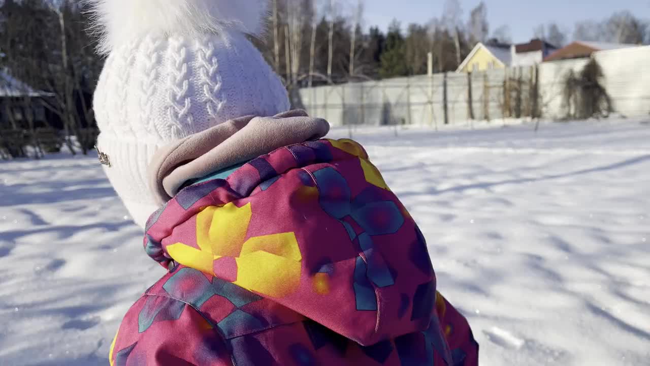 一个小女孩在明亮的阳光下在雪地里跑来跑去视频素材