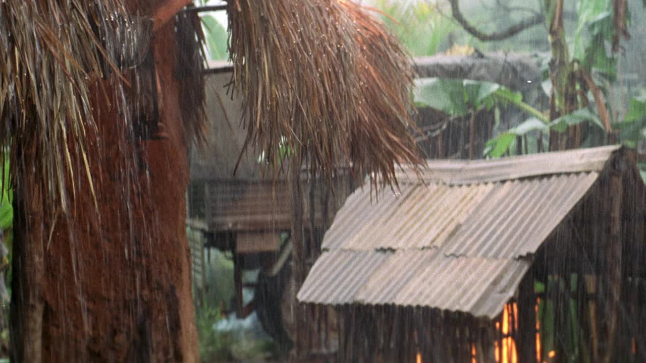 中角村在雨中。铁皮屋顶和草屋顶或稻草屋顶的小屋。木结构建筑和植物在bg燃烧。视频素材