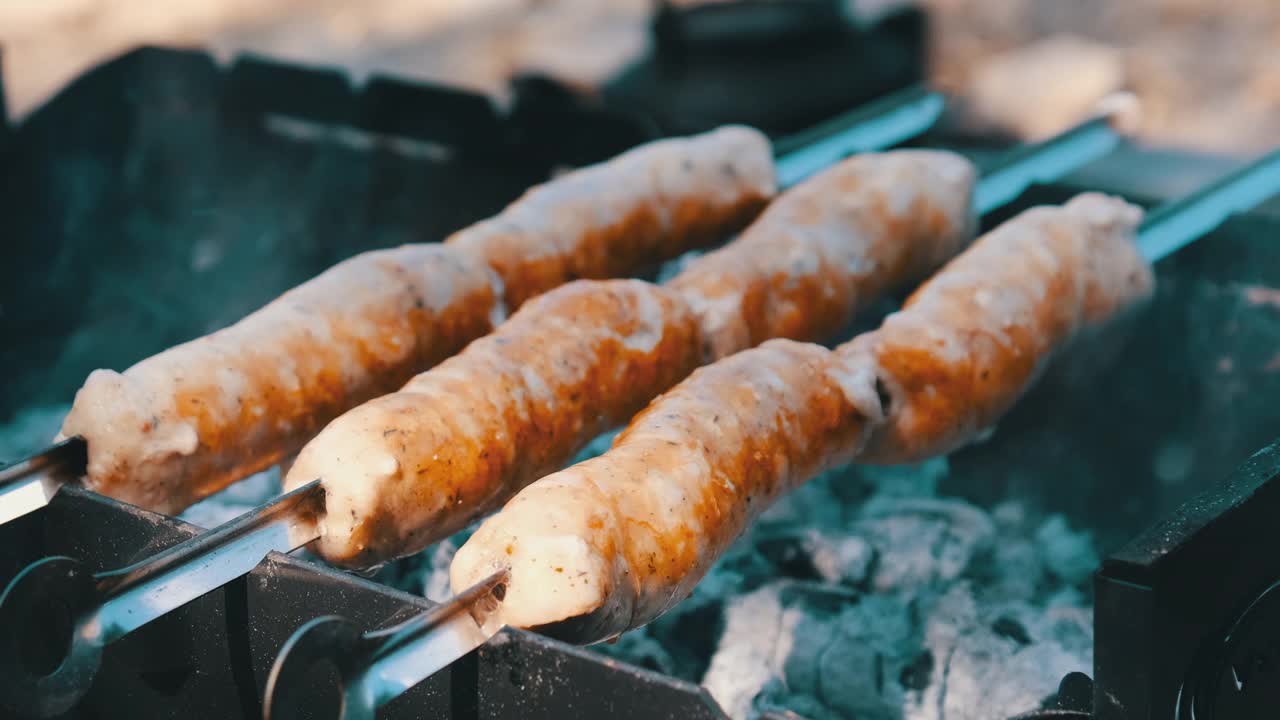 在烤肉串上的香肠是在户外便携式烤架上烤的，近距离，烧烤视频素材