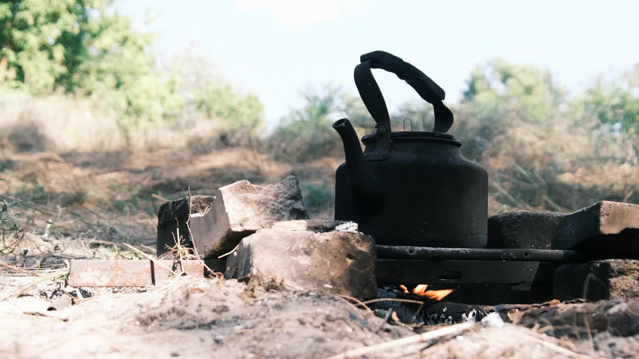 旅游水壶站在一个自制的篝火炉在旅游营地的自然视频素材