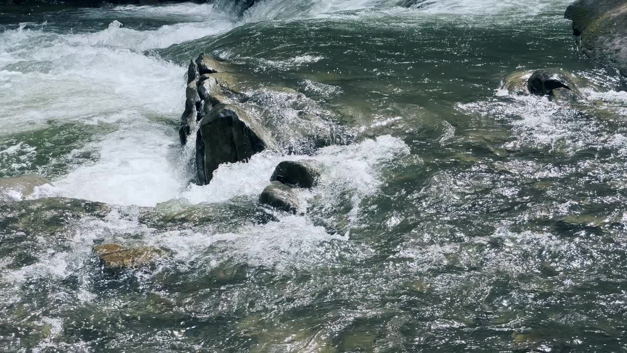 水纹理在清澈的溪流在山石。河水在急流中流动。视频素材