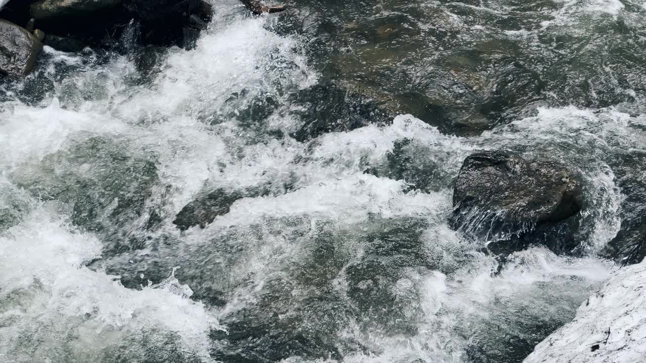 在水流湍急的河流。在暴风雨的水流中潮湿的卵石。特写泡沫河激流。视频素材