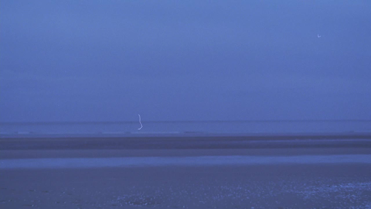 广角的空，沙滩。看到海浪在bg冲击着海岸。见抛撒在空中的五彩纸屑或小纸片。天空有雾，多云或阴天。海岸线。海中。96 FPS。视频素材