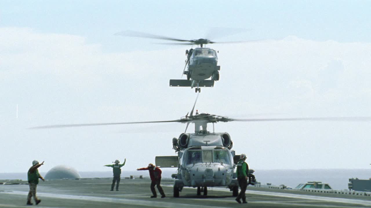 sh-60b海鹰直升机广角降落在哈利s.杜鲁门号航母甲板上。飞行甲板乘务人员发出或指示直升机降落。BG的海洋。蓝天白云。航空母舰。视频素材