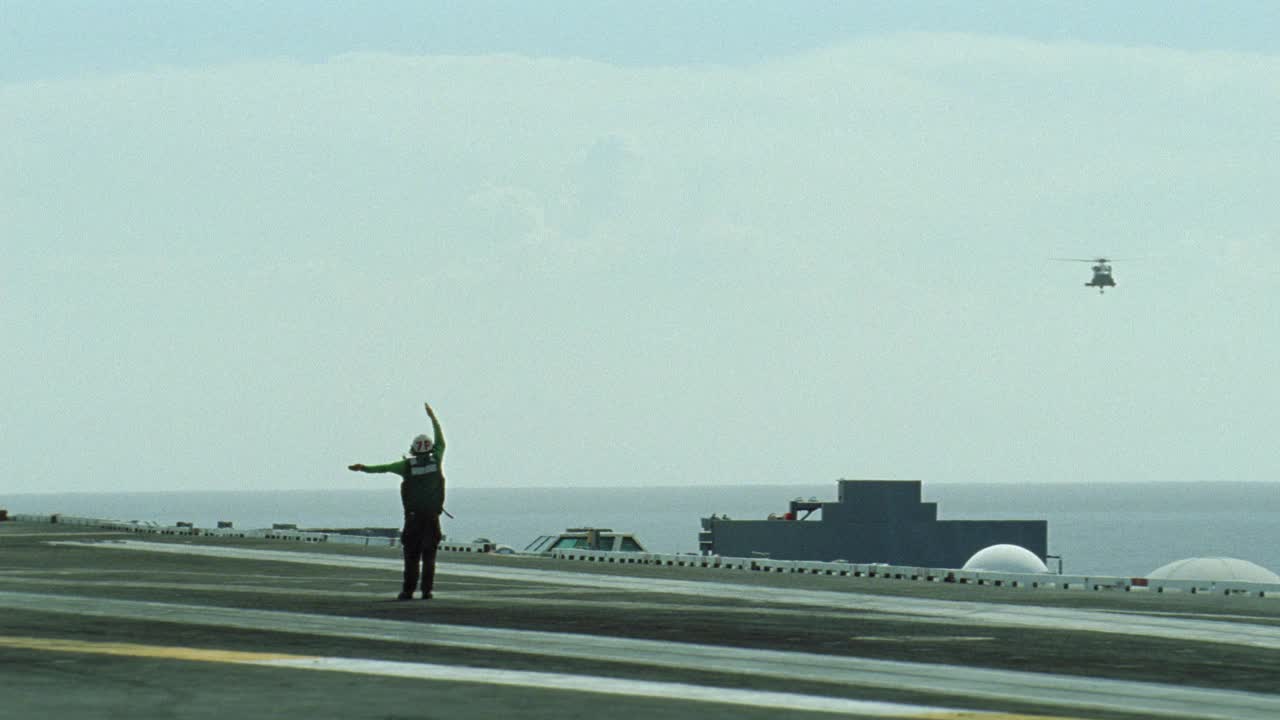 sh-60b海鹰直升机广角降落在哈利s.杜鲁门号航母甲板上。飞行甲板机组人员发出着陆信号或指示。BG的海洋。蓝天白云。航空母舰。视频素材