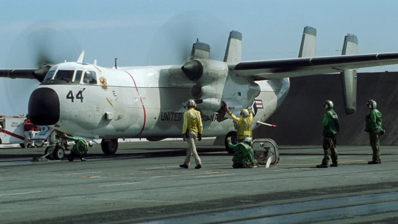 c-2a灰狗飞机从哈利s.杜鲁门号航空母舰的飞行甲板上滑行的广角镜头。机组人员协助。飞机起飞后留下一排排气管。船员们留在甲板上。BG的海洋。蓝天白云。航空母舰。视频素材